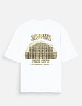A white short-sleeve t-shirt with a vintage-style graphic of Jaipur's Pink City palace on the back, featuring the text 'JAIPUR' and 'PINK CITY' in a warm beige and brown color palette.