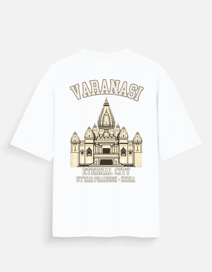 A white short-sleeve t-shirt with a beige graphic print of the Varanasi Temple and text reading 'VARANASI' and ETERNAL CITY', shown on a light gray background.