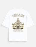 A white short-sleeve t-shirt with a beige graphic print of the Varanasi Temple and text reading 'VARANASI' and ETERNAL CITY', shown on a light gray background.