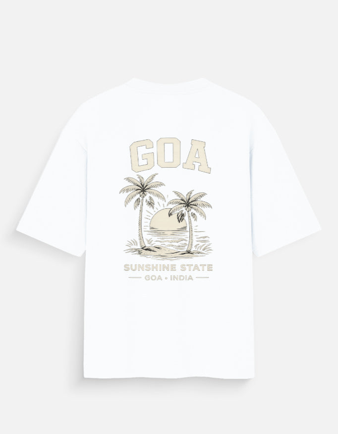A white short-sleeve t-shirt shown from the back, featuring a beige graphic print of two palm trees, a sunset, and the text 'GOA' and 'SUNSHINE STATE GOA INDIA'.