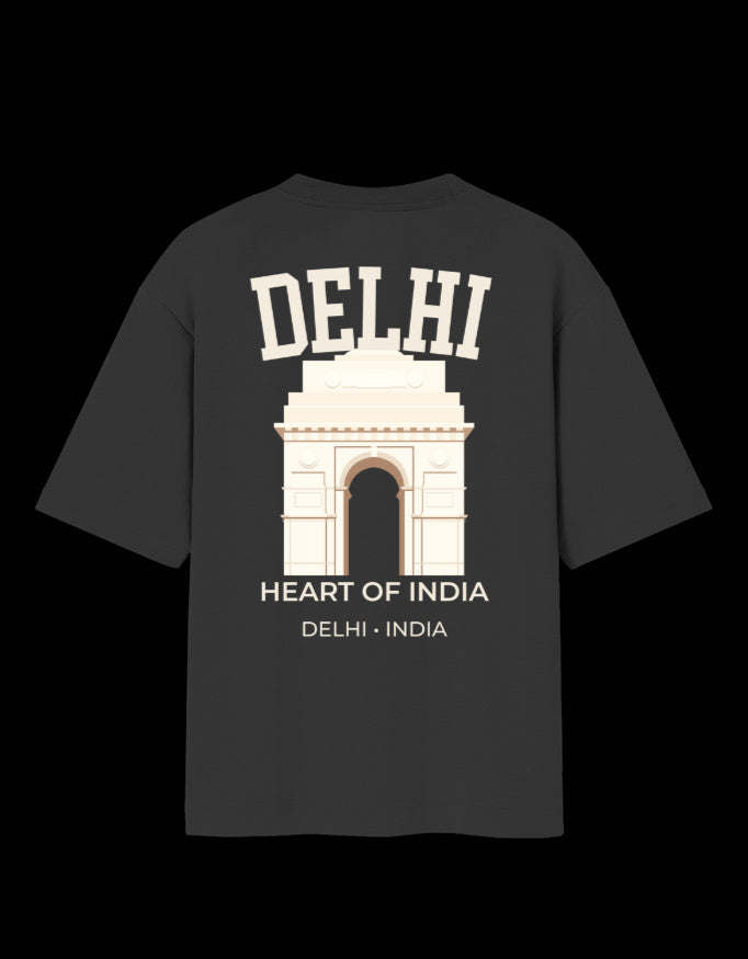 A dark charcoal gray t-shirt with a cream-colored graphic of the India Gate monument in Delhi, featuring the text 'DELHI' and 'HEART OF INDIA' on a solid black background.