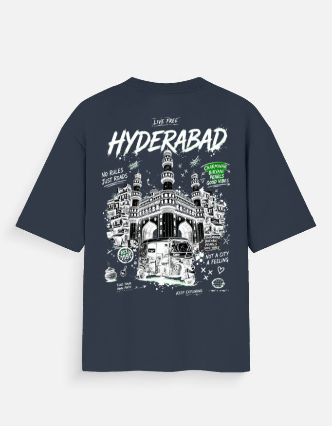A navy blue short-sleeve t-shirt shown from the back, featuring a large white and green graphic print of the Hyderabad Fort with text including 'HYDERABAD' and 'I LOVE FREE'.