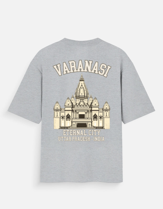 A light gray heather t-shirt shown from the back, featuring a cream-colored graphic print of the Varanasi temple with the text 'VARANASI' and 'ETERNAL CITY UTTAR PRADESH - INDIA'.