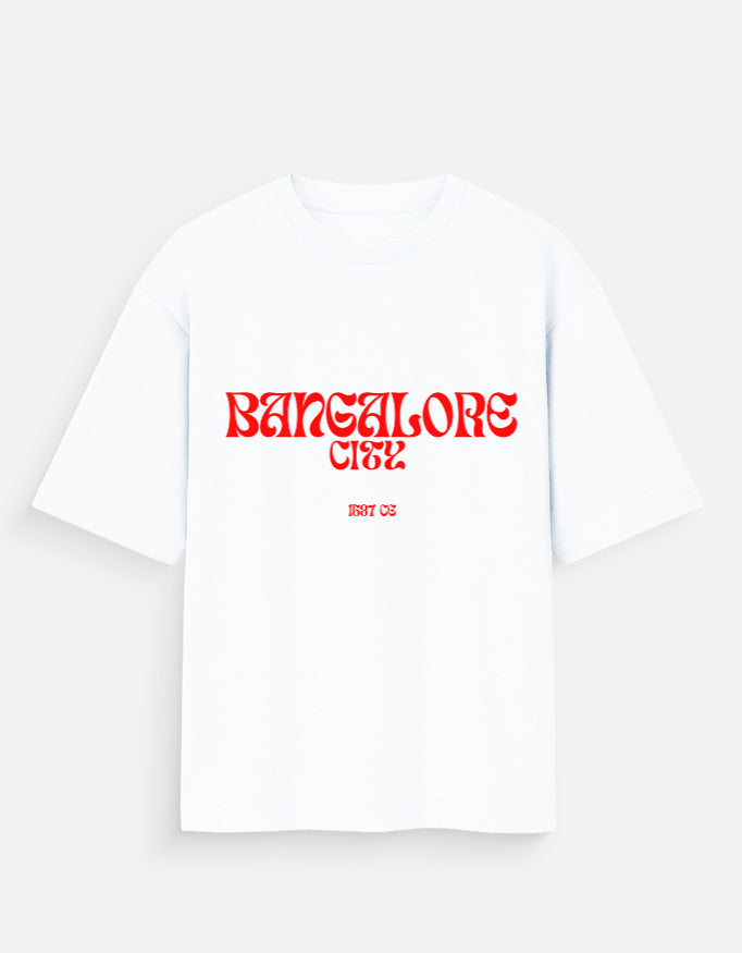 A white short-sleeve t-shirt with 'BANGALORE City
' printed in a red stylized font across the chest, and 'EVT 02' in smaller red text below it, displayed on a light gray background.