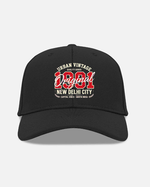 A black baseball cap with a curved brim, featuring a red and white graphic on the front that reads 'Urban Vintage 1981 New Delhi City' with 'Capital Vibe - North India' below, shown against a light gray background.