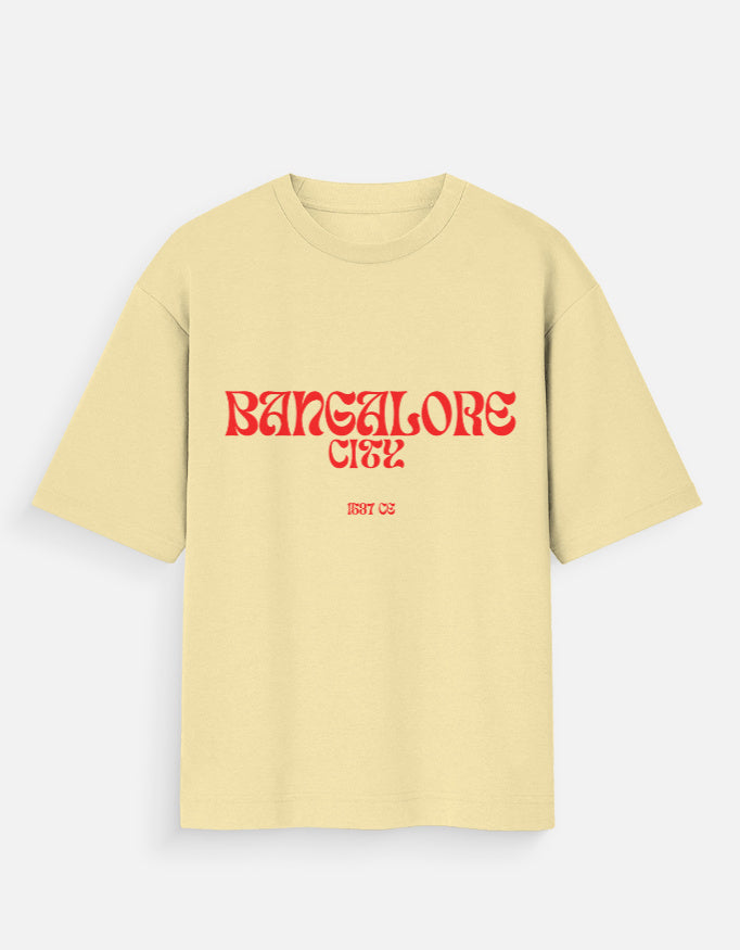 A pale yellow short-sleeve t-shirt with 'BANGALORE CTS2' printed in a red stylized font across the chest, on a light gray background.