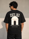A man viewed from behind wearing a black t-shirt with a large white graphic print of the Delhi Arch and the text 'DELHI HEART OF INDIA'.