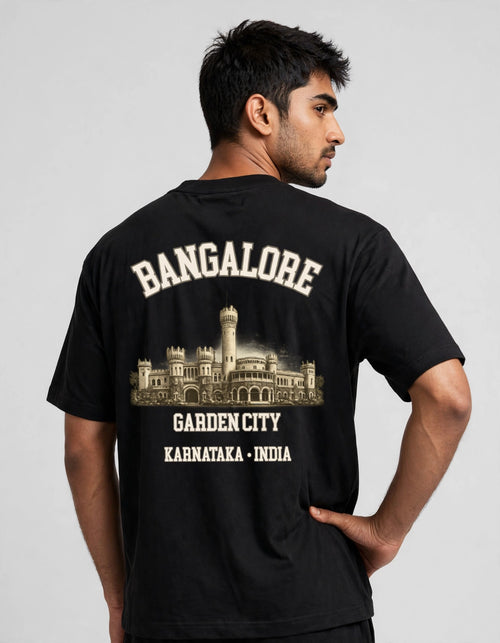 A man wearing a black t-shirt from the back, featuring a cream-colored graphic print of Garden City, Bangalore, with the text 'BANGALORE', 'GARDEN CITY', and 'KARNATAKA - INDIA'.