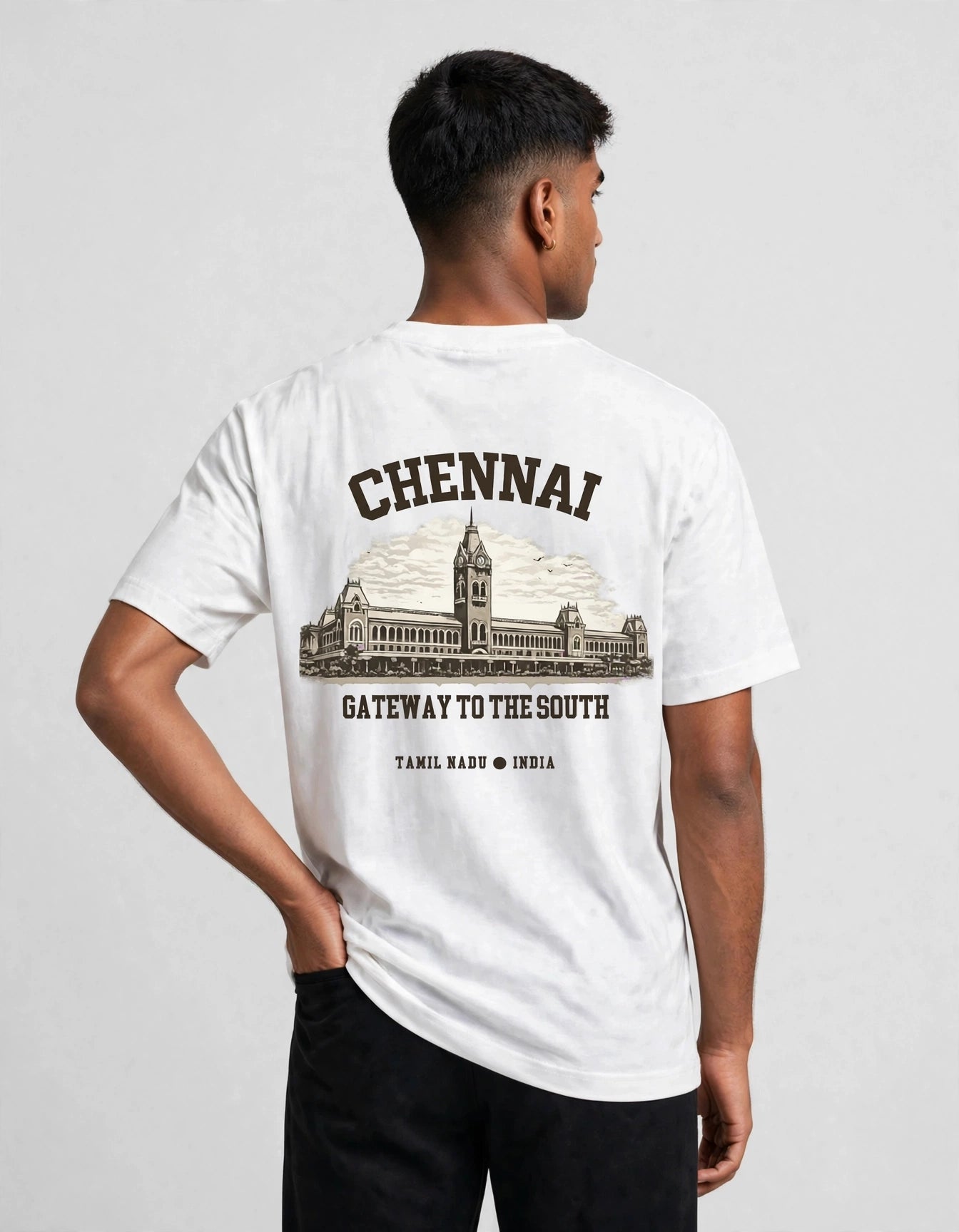 A man wearing a white short-sleeve t-shirt with a black graphic print on the back, featuring the word 'CHENNAI' above an illustration of a historic building and the text 'GATEWAY TO THE SOUTH'.