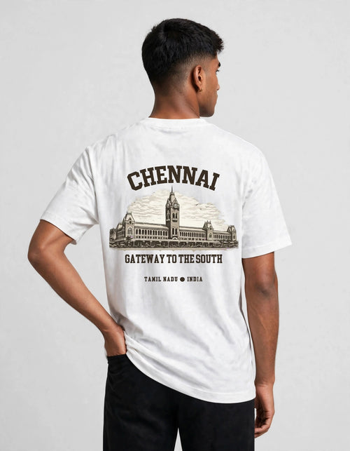 A man wearing a white short-sleeve t-shirt with a black graphic print on the back, featuring the word 'CHENNAI' above an illustration of a historic building and the text 'GATEWAY TO THE SOUTH'.