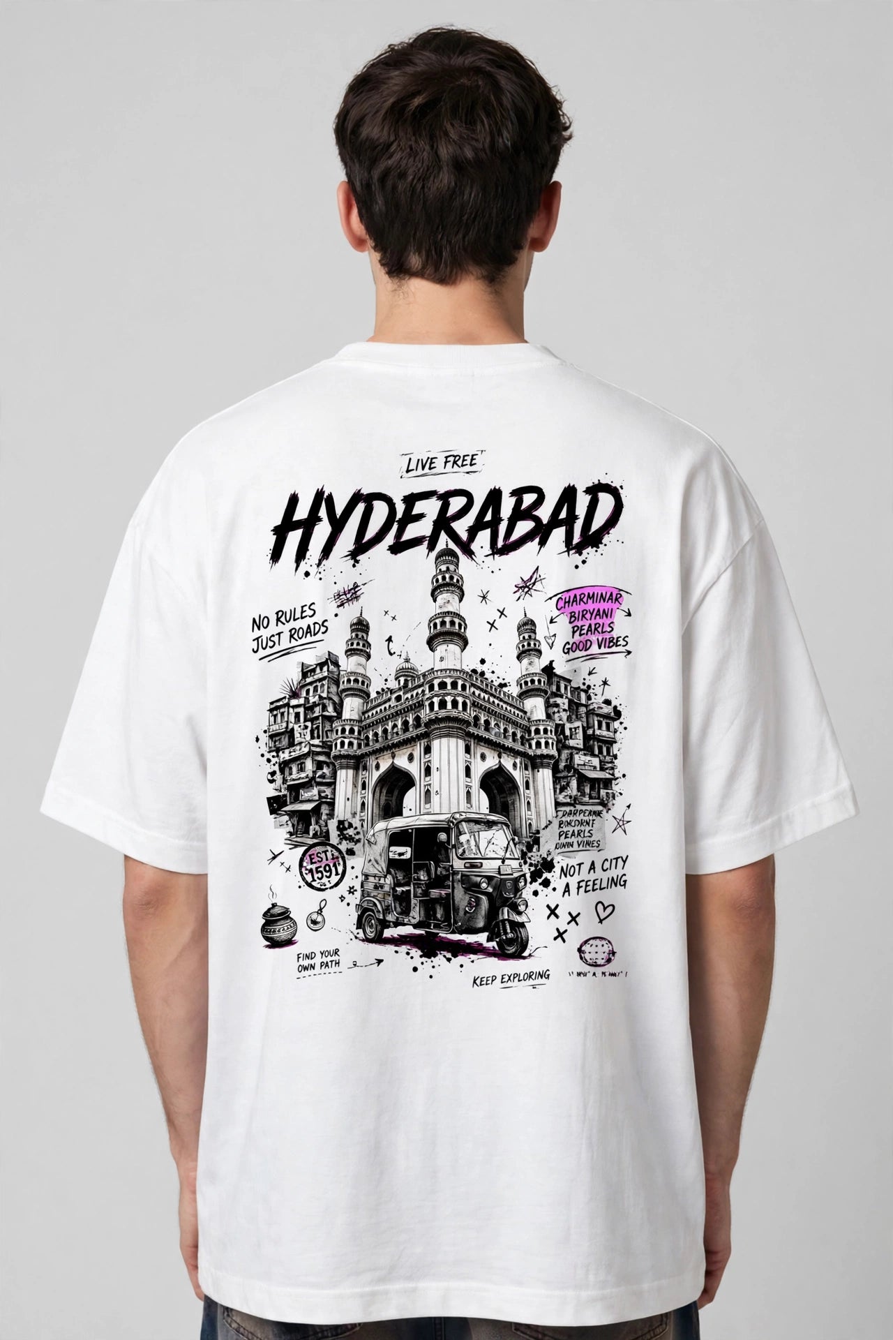 A man viewed from behind wearing a white t-shirt with a large black and purple graphic print on the back featuring the text 'HYDERABAD' and an illustration of a historic building and vehicle.