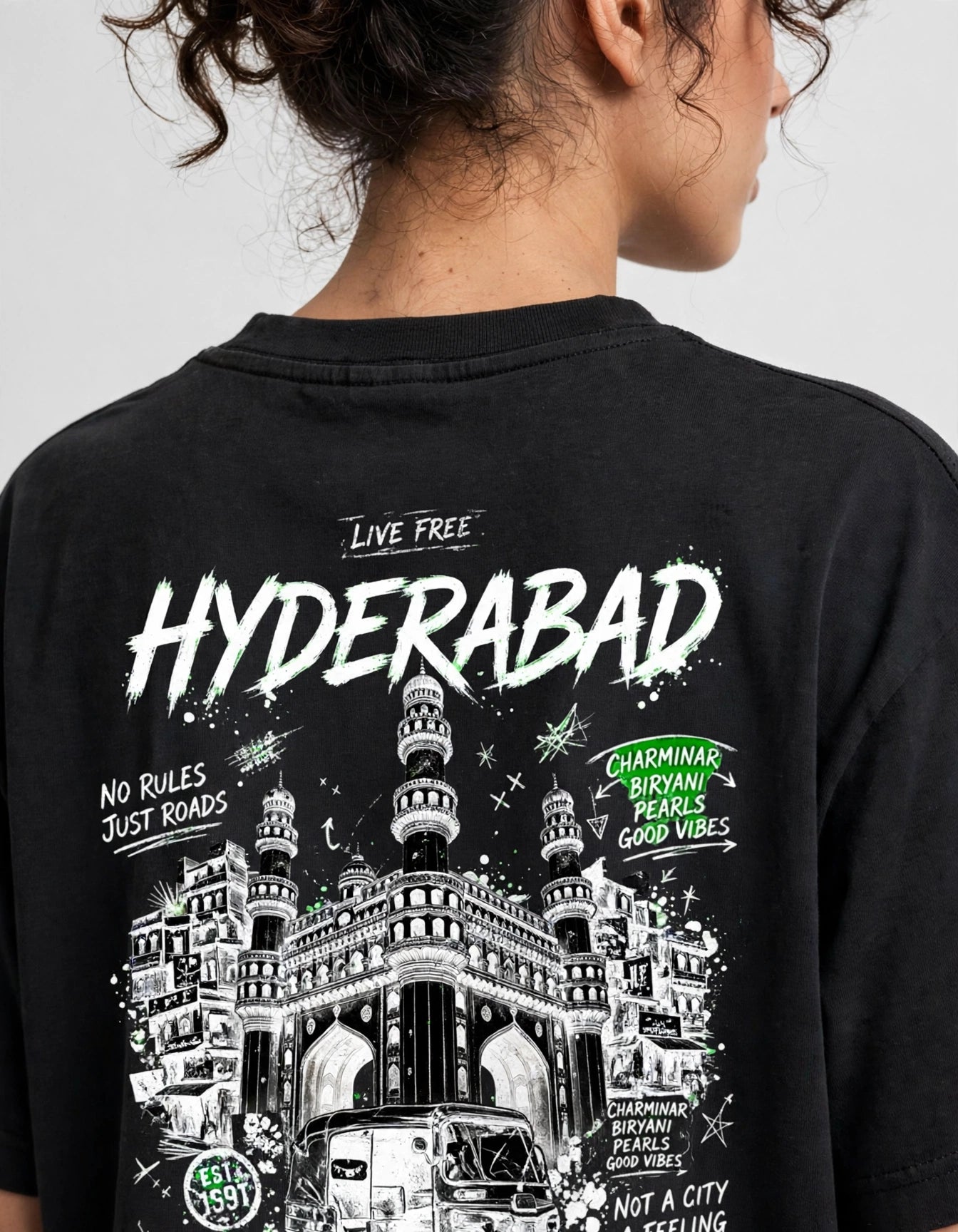 A person shown from the back wearing a black graphic T-shirt with a large white and green illustration and text reading 'HYDERABAD' and 'LIVE FREE'.