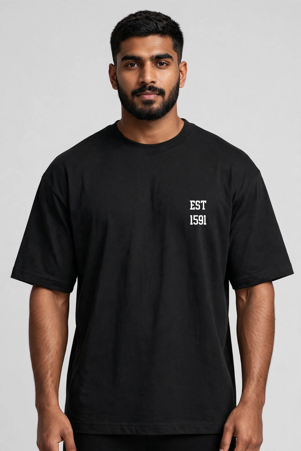 A man wearing a black short-sleeve t-shirt with 'EST 1591' printed in white on the left chest, photographed against a neutral gray background.