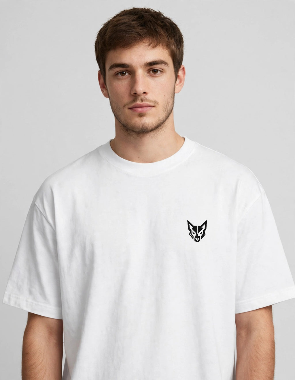 A man wearing a white crewneck t-shirt with a small black wolf head logo on the left chest, photographed against a neutral light gray background.