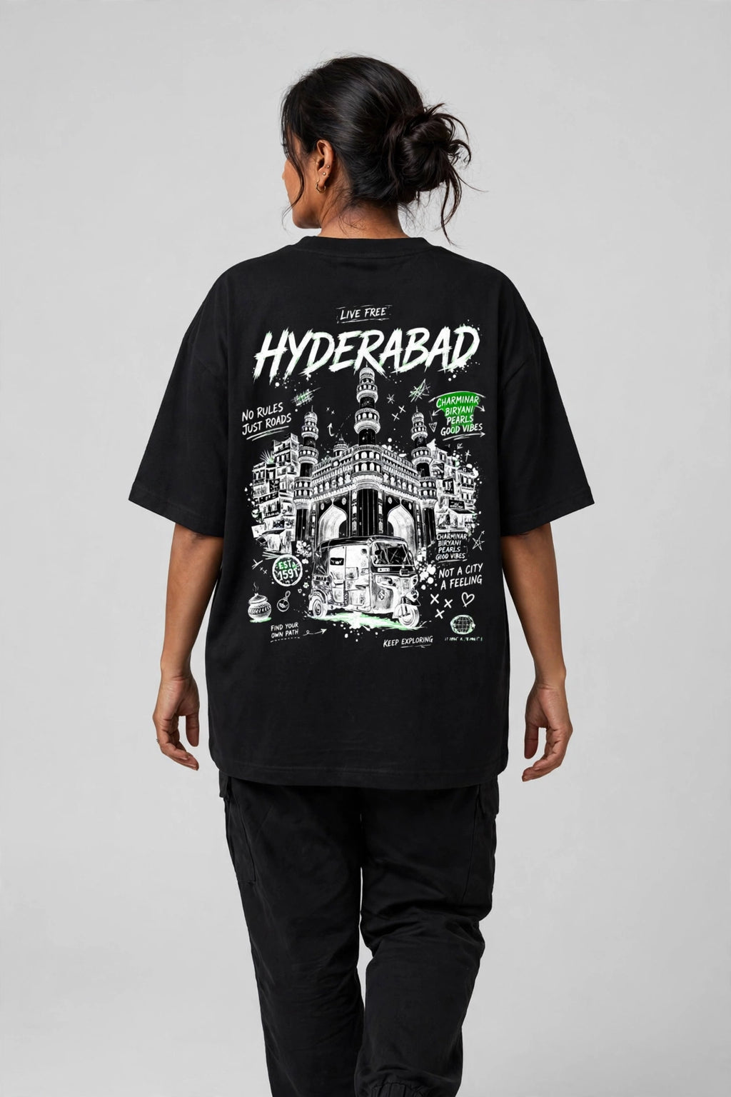 A person shown from the back wearing an oversized black T-shirt with a large white and green graphic print on the back reading 'HYDERABAD' and 'LIVE TRUE'.